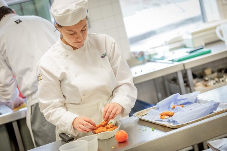 A chef preparing some chicken in a kitchen.